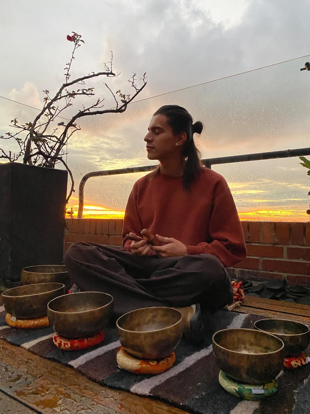 Daniel medita al atardecer rodeado de cuencos